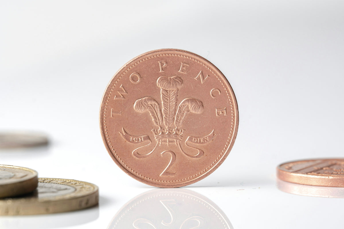 British two pence coin standing upright with blurred coins