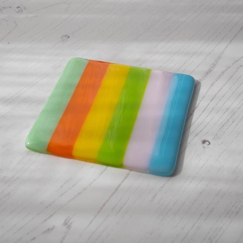 Vibrant striped fused glass coaster, handmade British craft on whitewashed wood