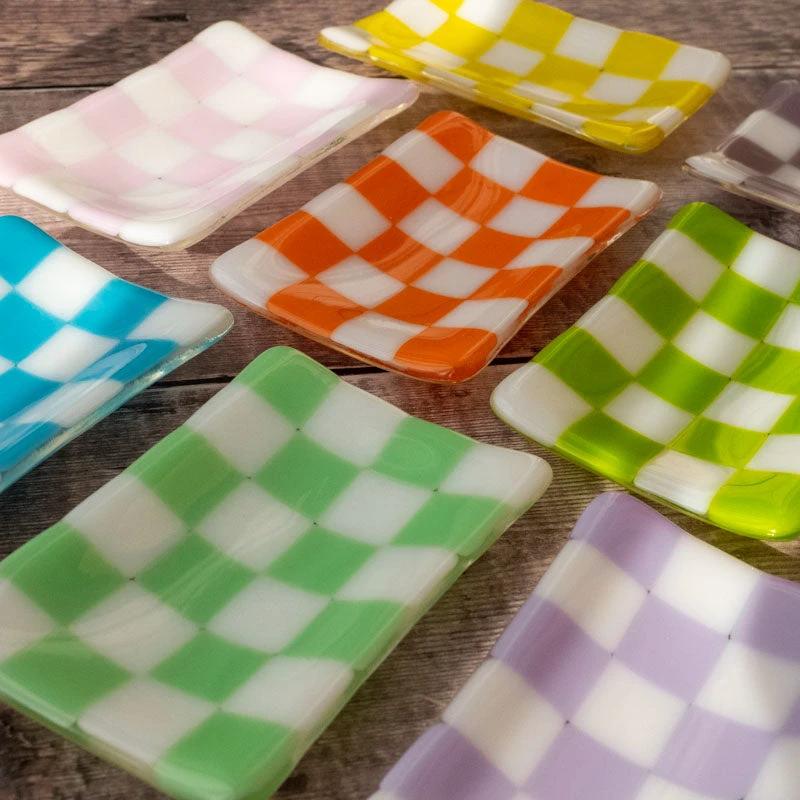 Colorful checkered glass dishes in pink, orange, green, blue, yellow, and purple on rustic wood