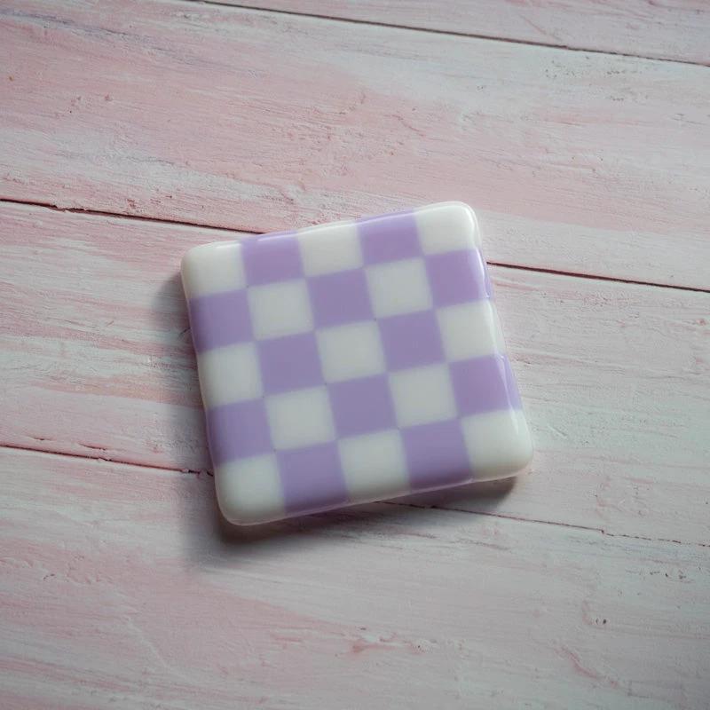 Purple and white checkered glass coaster on pink wood, handmade British craft