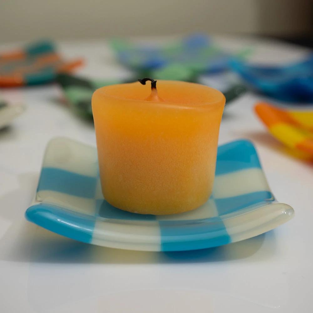 Orange candle on blue and white checkered glass dish, handmade British craft