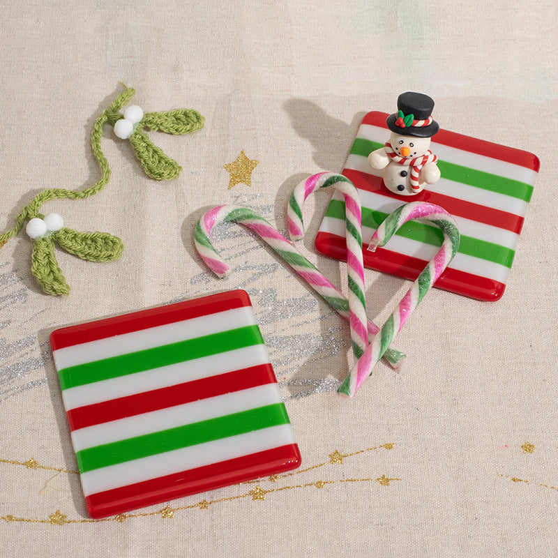 Red green striped glass coasters with snowman, candy canes, and crocheted mistletoe on festive fabric