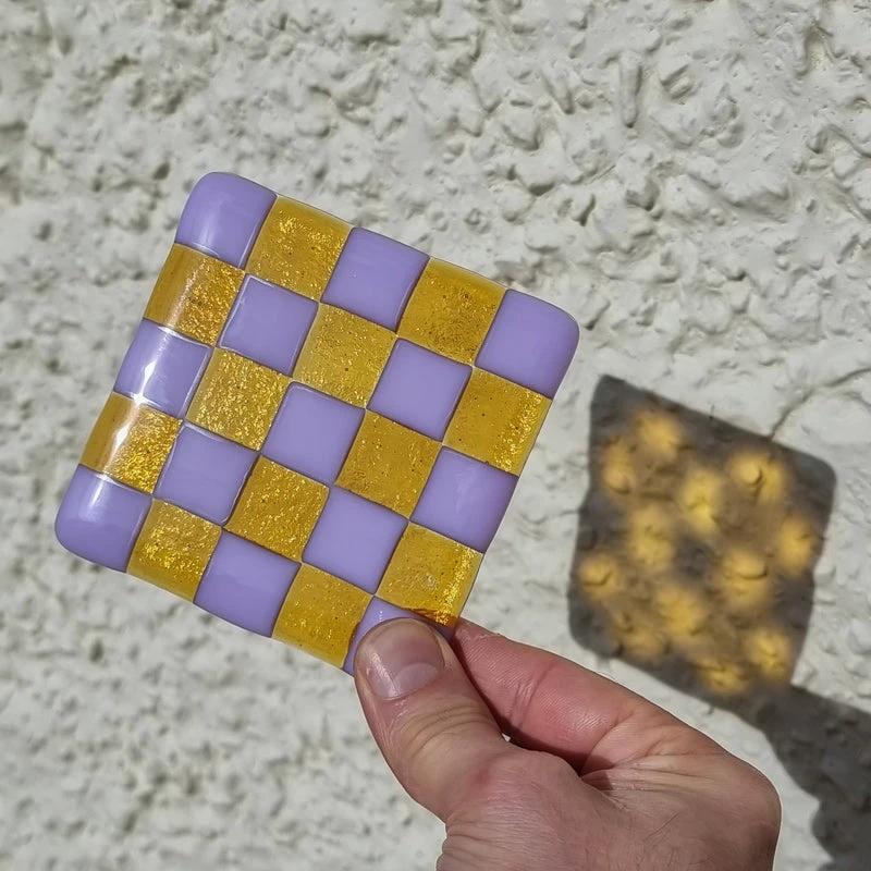 Hand holding purple and gold checkered fused glass coaster, handmade British craft
